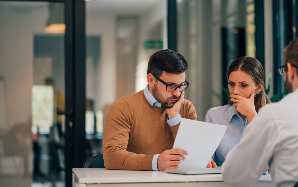 A couple reviews a document with a financial professional during a meeting, illustrating financial planning and decision-making.