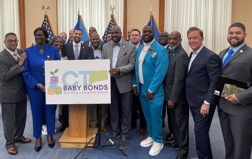 Baby Bonds Colorado Connecticut leaders and community advocates gather at the State Capitol holding a “CT Baby Bonds: Building a brighter future” sign.